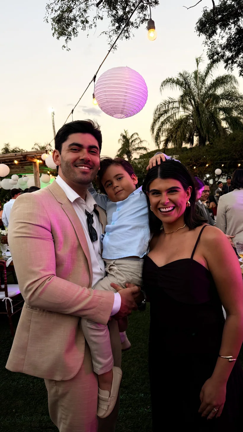 Guilherme Cirilo com a esposa e o filho no colo, numa festa ao ar livre no fim de tarde